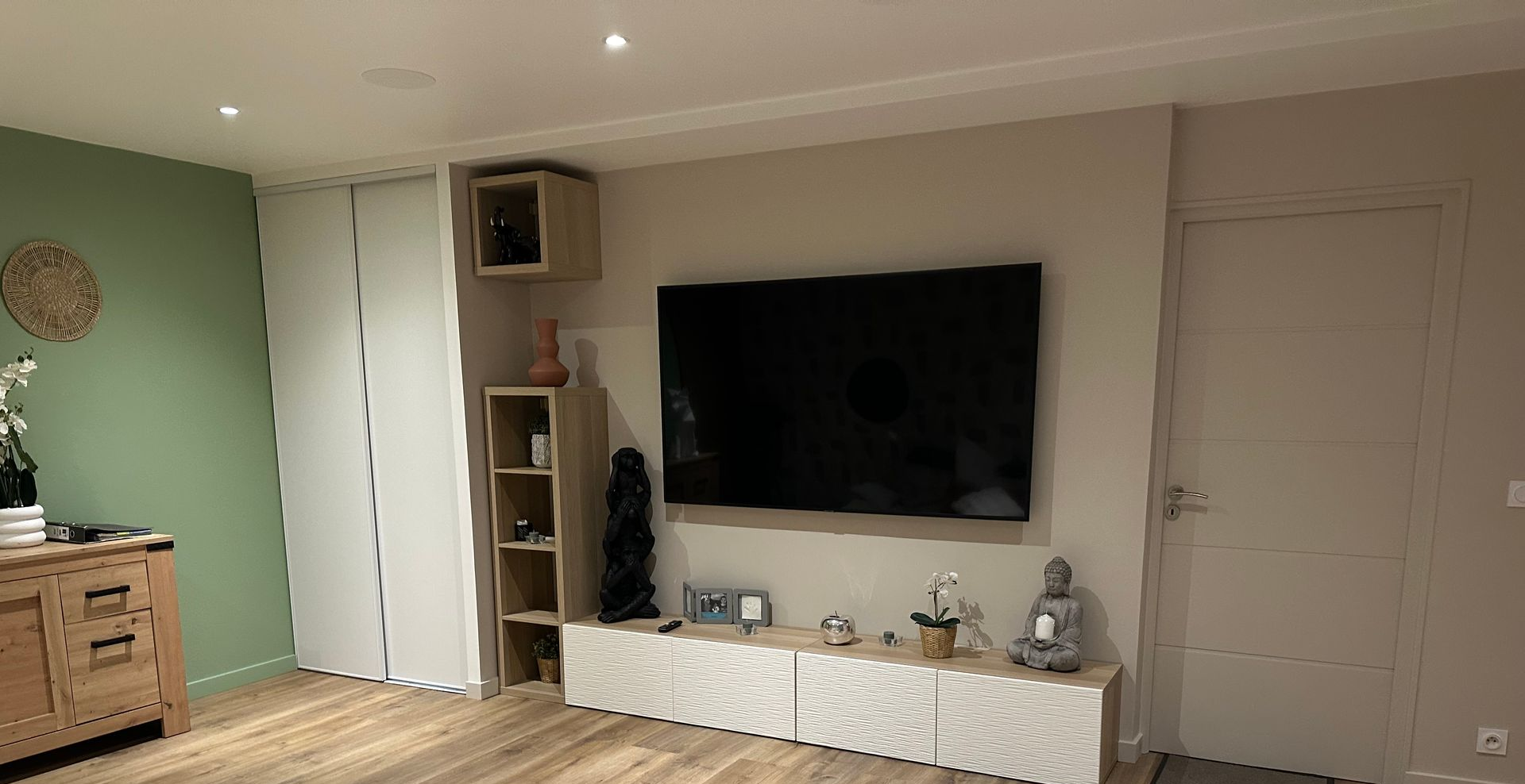 Salon avec télévision murale, console, parquet et mur d'accent.