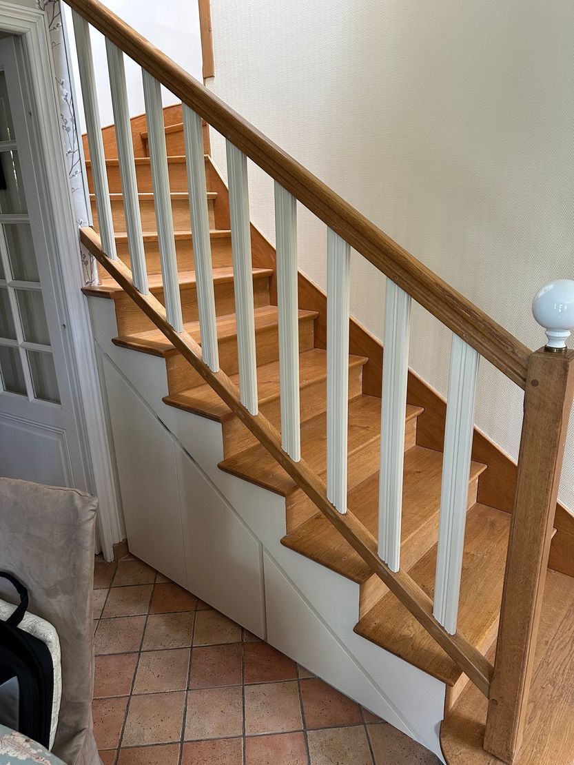 Escalier en bois avec balustres et sol carrelé dans un intérieur de maison.