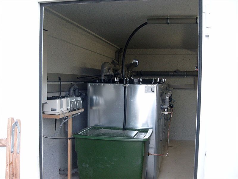 Ein Edelstahltank mit einer grünen Tonne davor