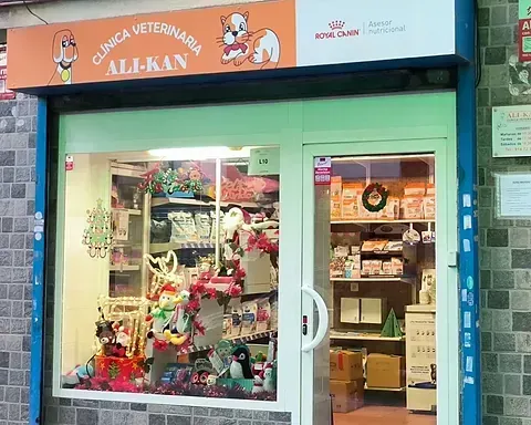 Una clínica veterinaria llamada Ali-Kan, con un escaparate decorado. La puerta de la tienda es blanca y está iluminada.