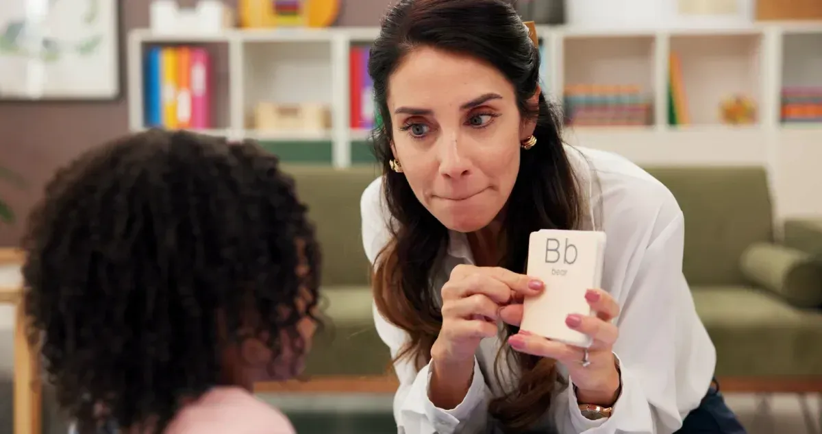 Maestra sosteniendo una tarjeta con la letra 