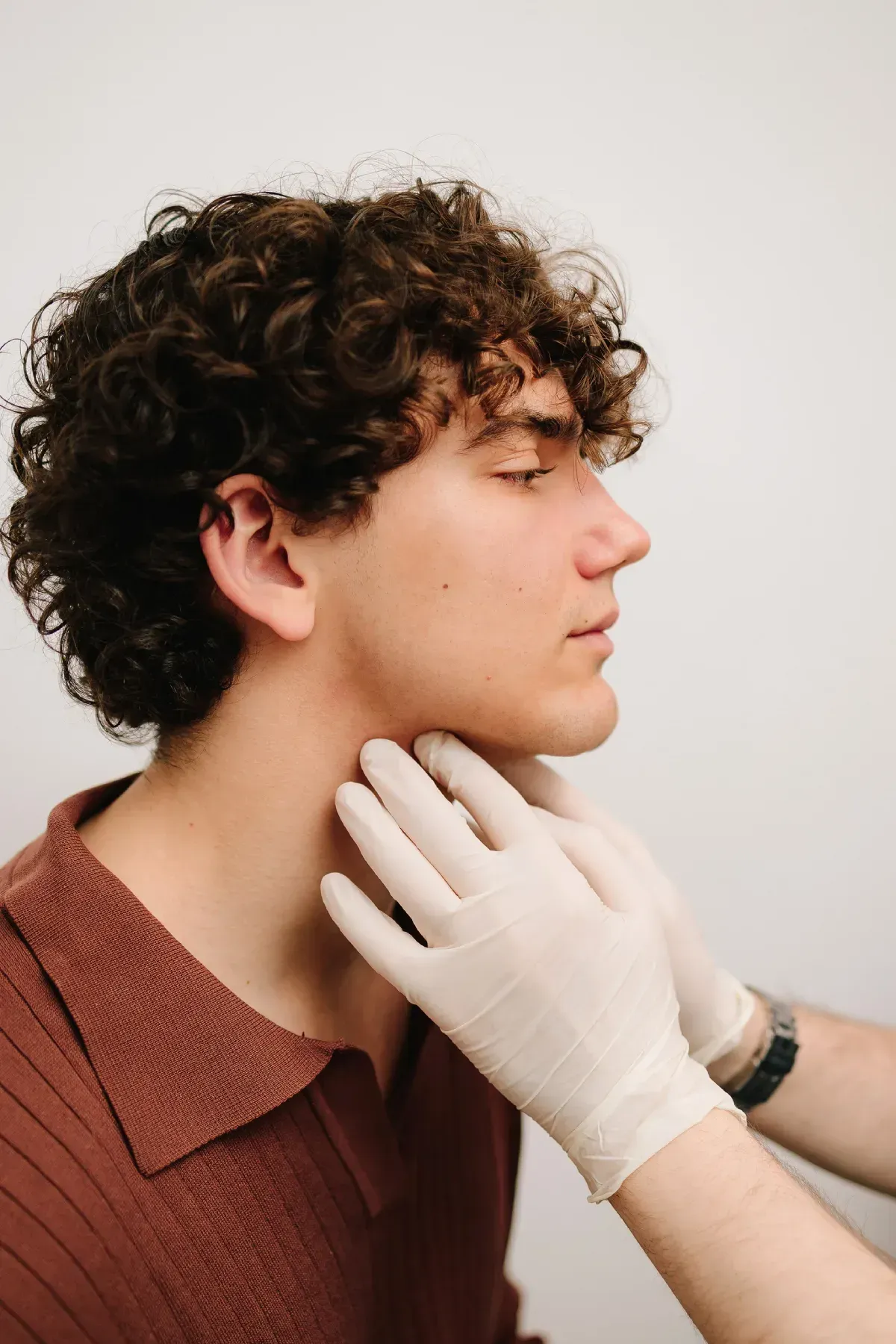 El cuello de una persona siendo examinado por manos enguantadas.