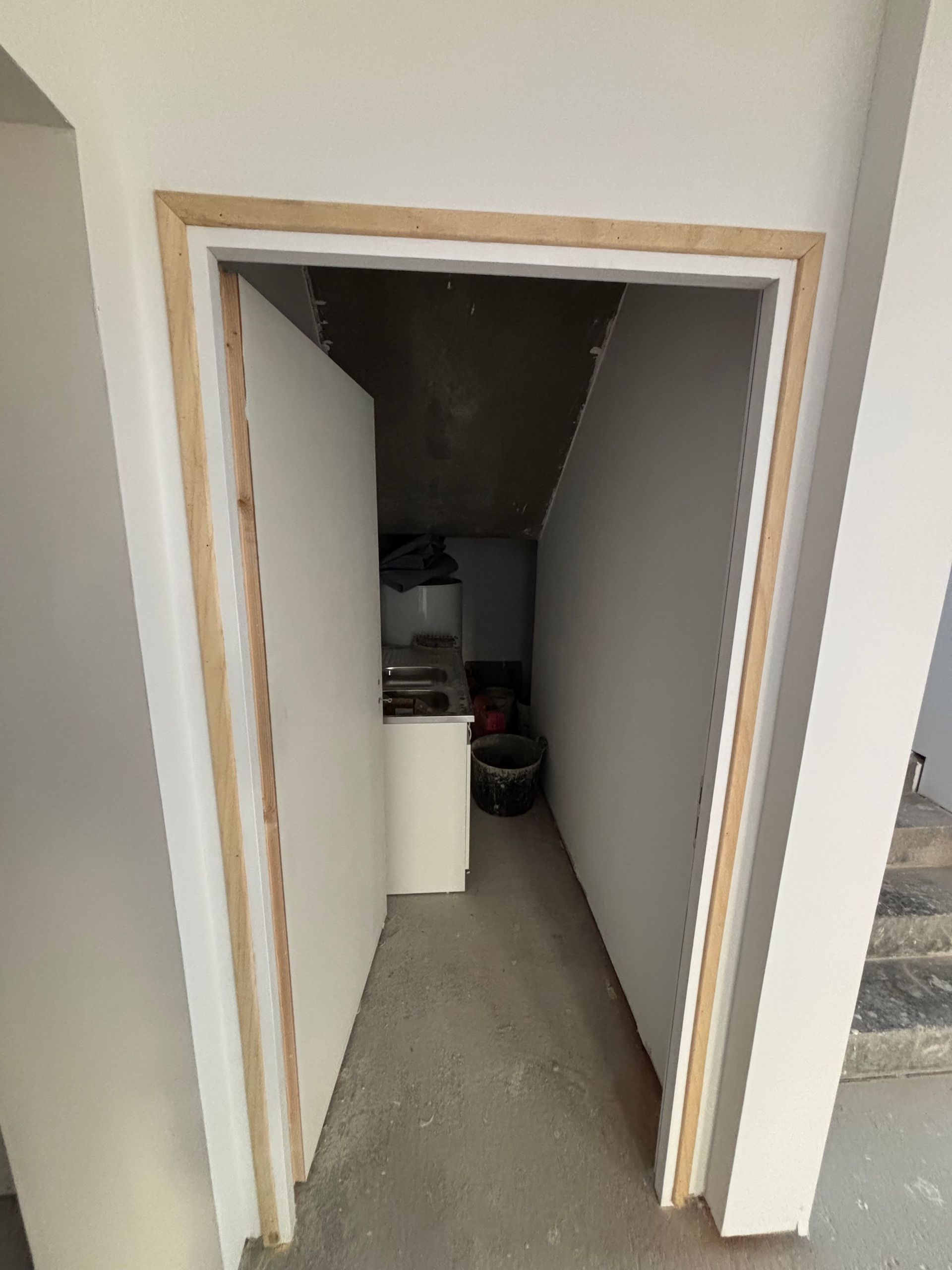Niche de placard étroite avec des murs blancs, des moulures beiges et un petit appareil électroménager ou des objets de rangement au fond.