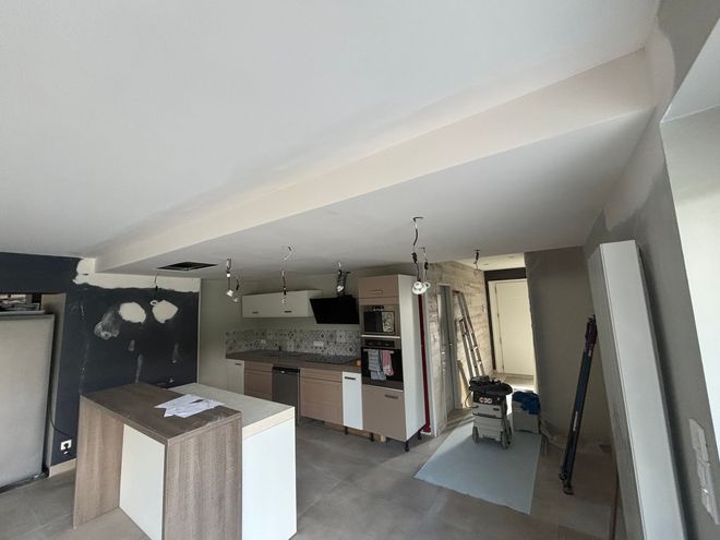 Couloir de bureau vide avec des pièces aux parois vitrées, des dalles de plafond blanches et des cartons empilés sur la droite.