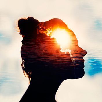 Una doble exposición de la cabeza de una mujer con el sol brillando a través de ella.