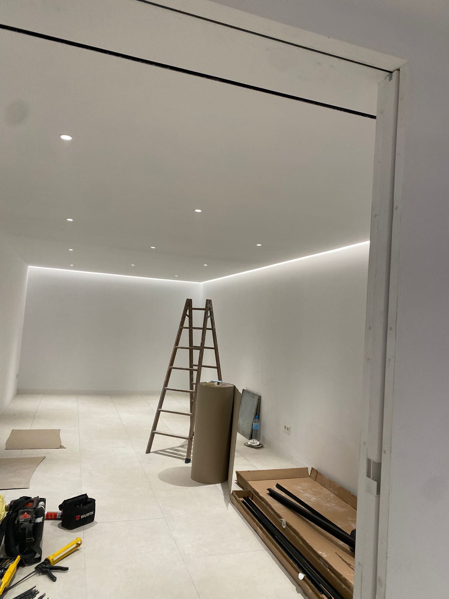 Habitación en construcción con escalera, materiales e iluminación empotrada.