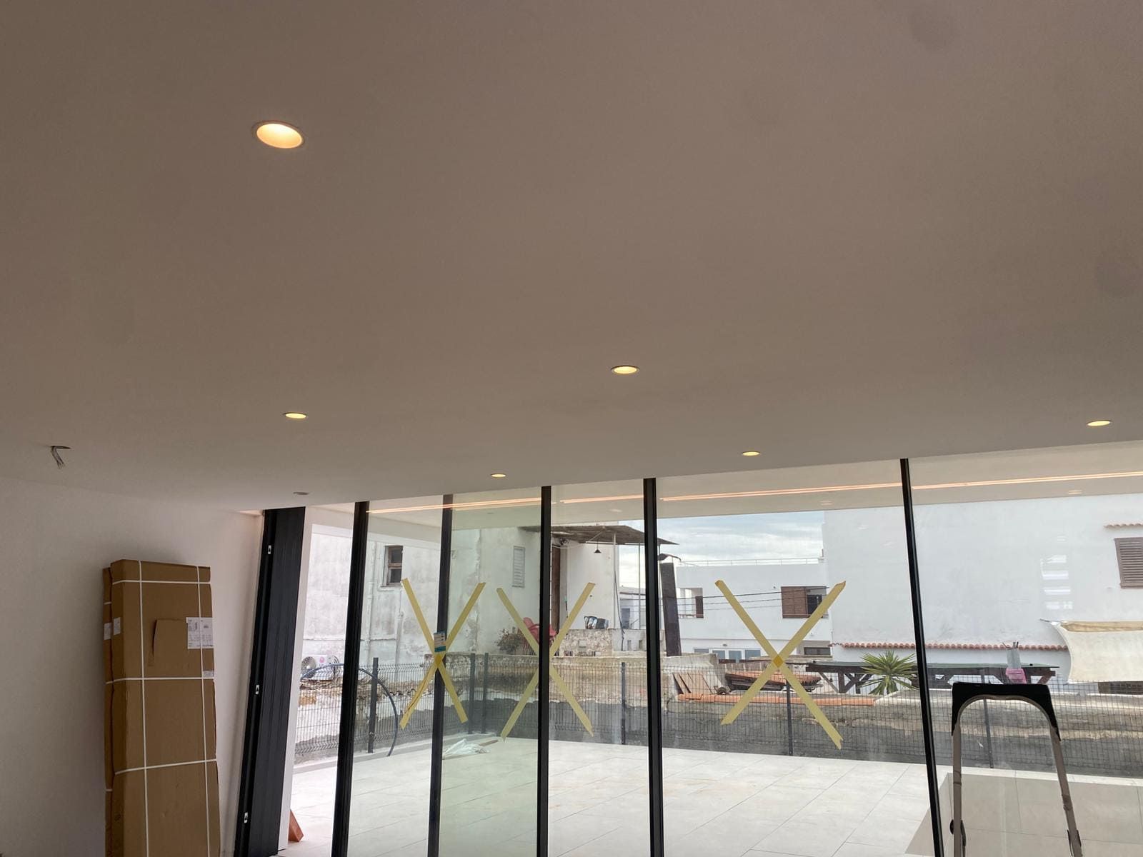 Interior con luces empotradas en el techo, puertas de cristal y una caja de cartón.