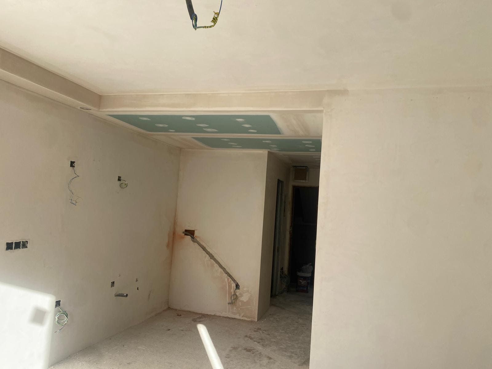 Interior de una habitación en construcción con paredes, techo y puerta parcialmente terminados.