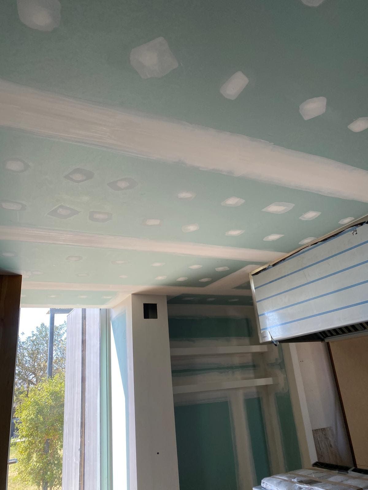 Techo con parches de yeso y cinta adhesiva. Paneles de yeso azul verdoso, masilla blanca, interior.