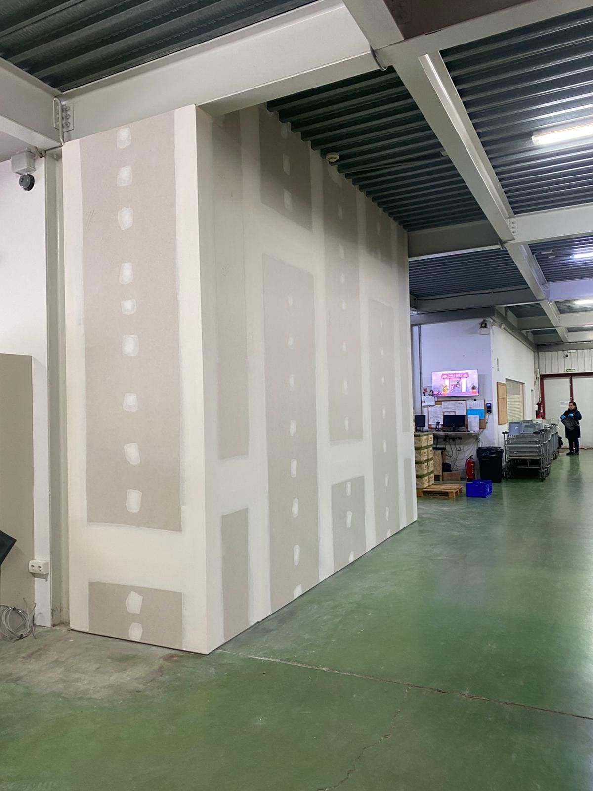 Hombre trabajando en el techo del baño, instalando paneles de yeso. Se ven el panel del techo, las lámparas y el espejo.