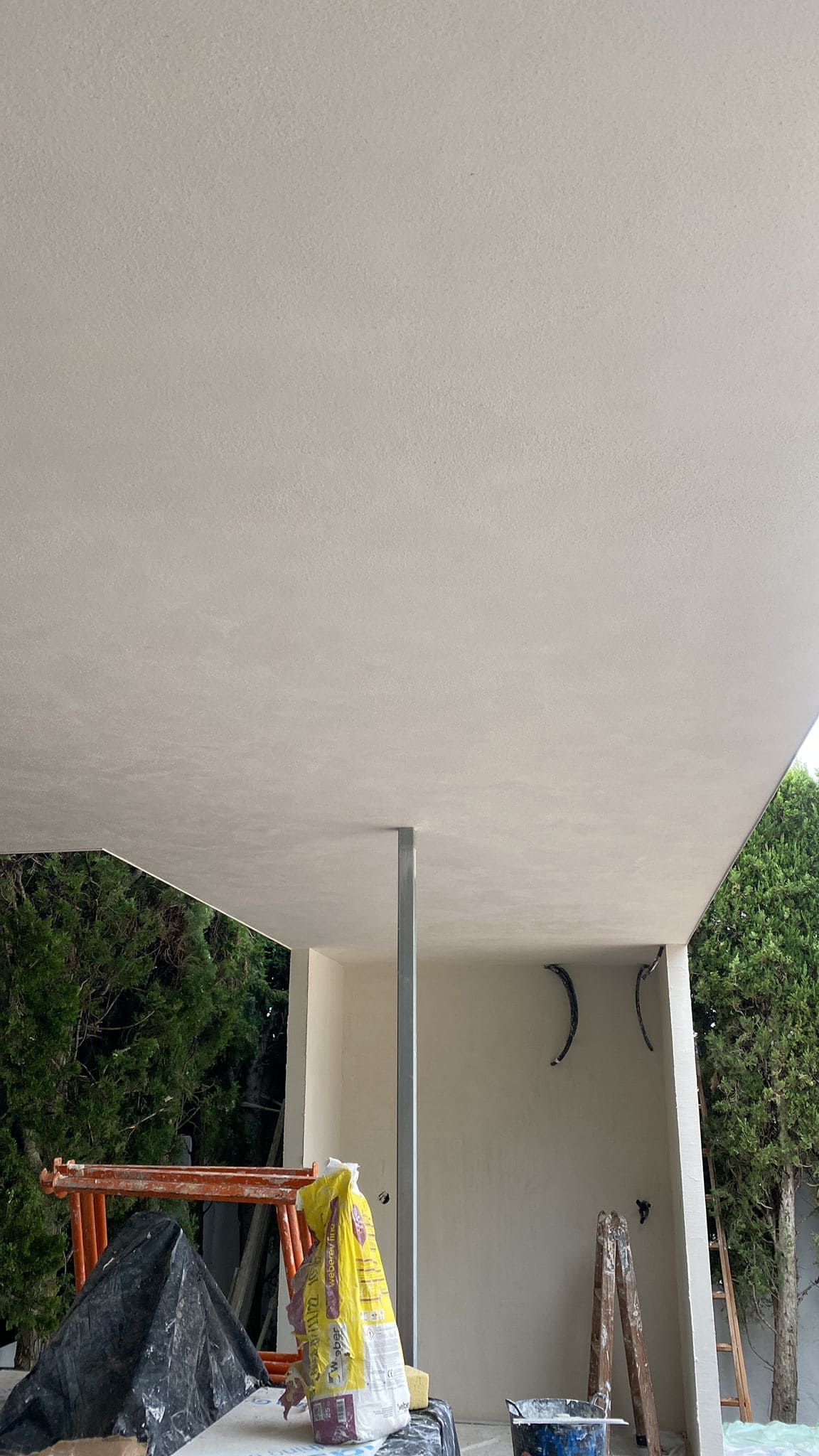 Obra: techo y pared recién enlucidos en tono beige, con andamios y materiales visibles.
