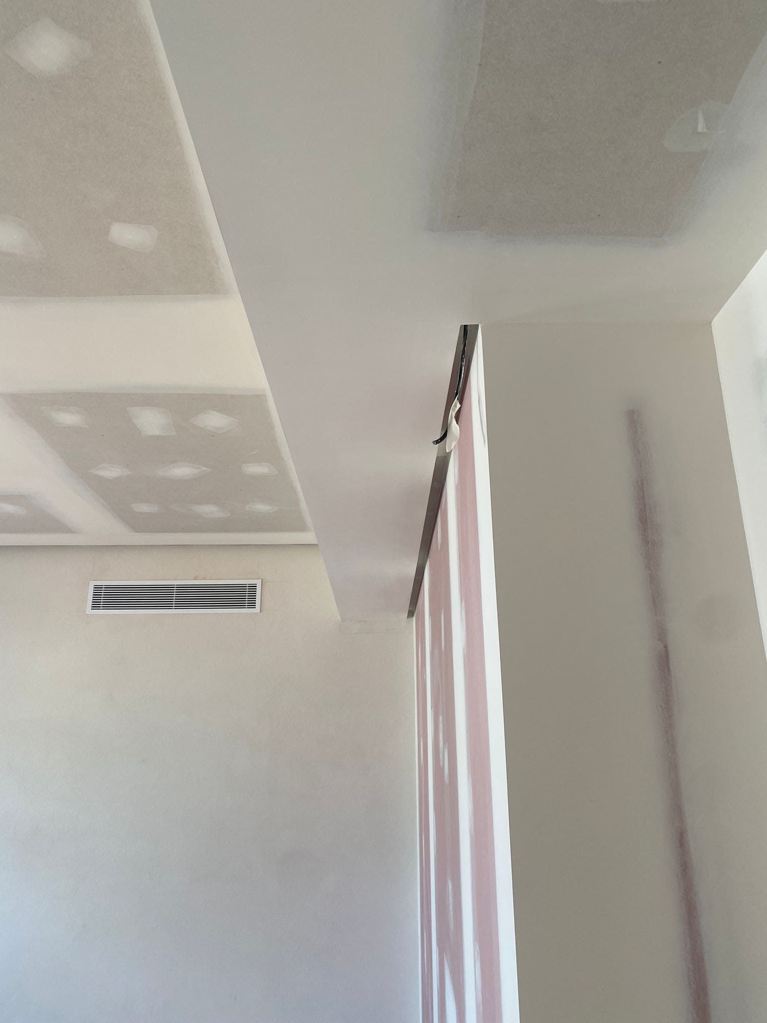 Andamio frente a un muro de piedra, bajo un techo blanco. Un cubo y herramientas descansan sobre la plataforma del andamio.