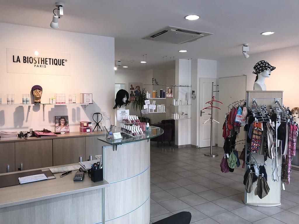 Intérieur d'un salon de beauté présentant des produits et accessoires capillaires. Couleurs neutres, éclairage vif et design moderne.