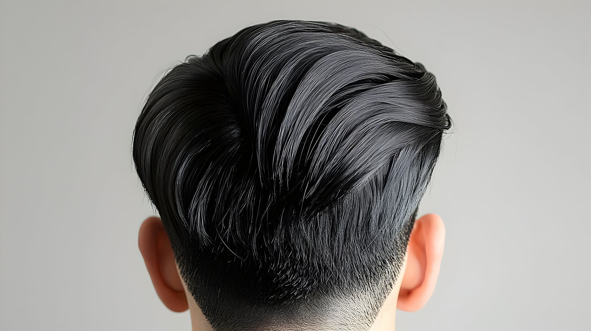 Vue arrière d'une tête aux cheveux foncés plaqués en arrière, teinture appliquée, et une ligne de cheveux effilée sur un fond gris clair.