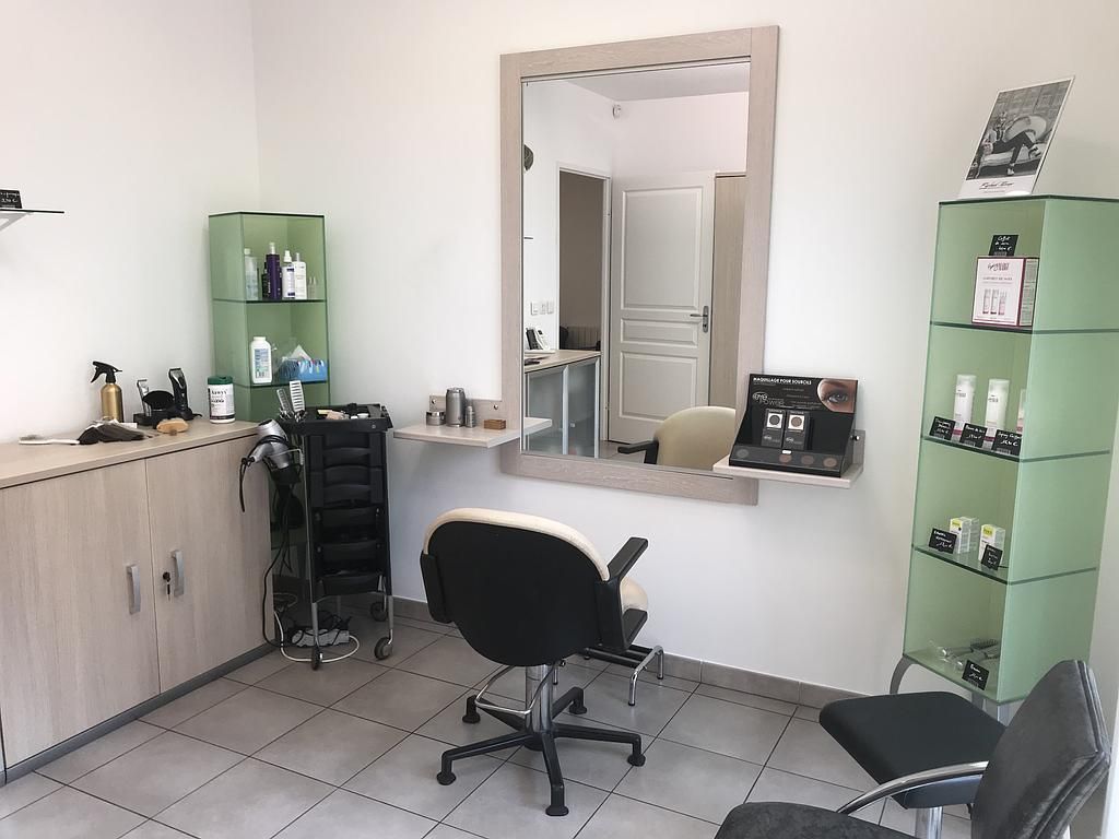 Intérieur d'un salon de coiffure avec miroir, fauteuil, étagères et produits de coiffage.