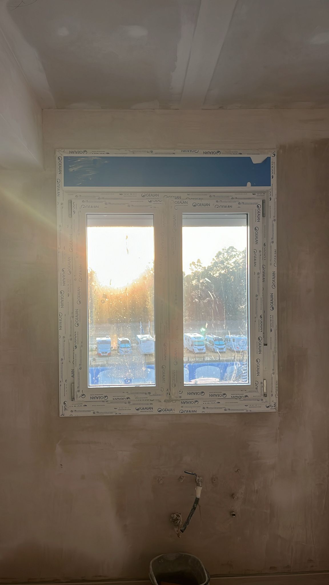 Ventana en una habitación con paredes de yeso sin terminar.