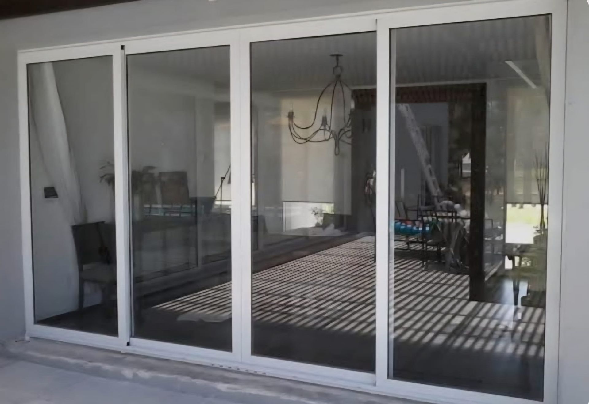 Puertas corredizas de vidrio con marco blanco que reflejan un espacio habitable interior.