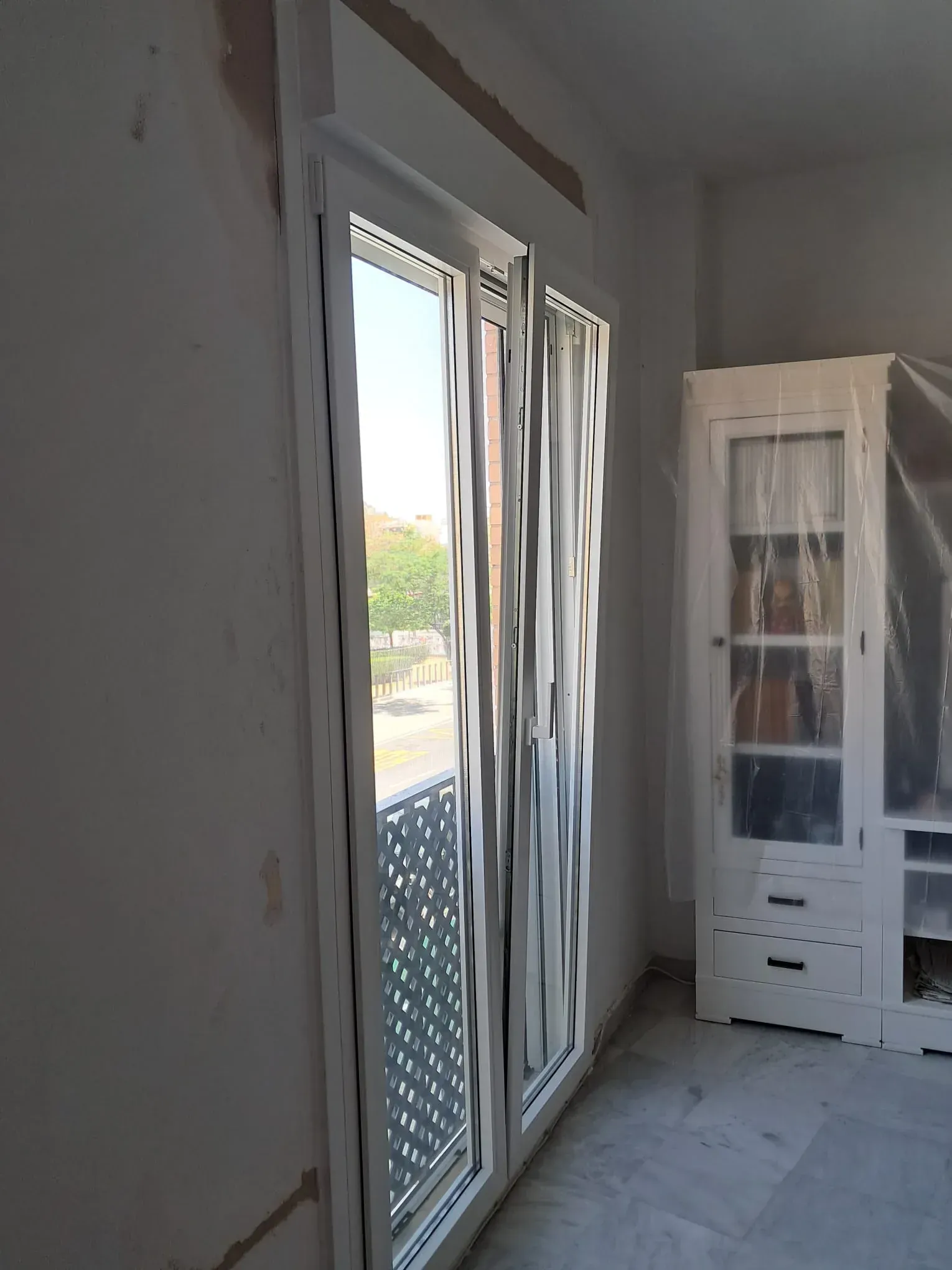 Puertas de balcón con marco blanco; mamparas onduladas blancas para mayor privacidad; armario empotrado blanco.