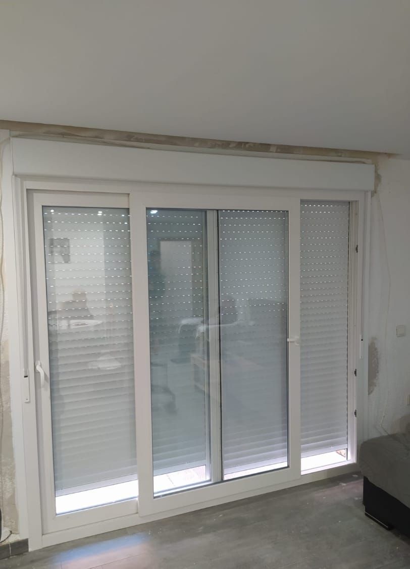 Puerta corrediza de cristal blanca con persianas cerradas.