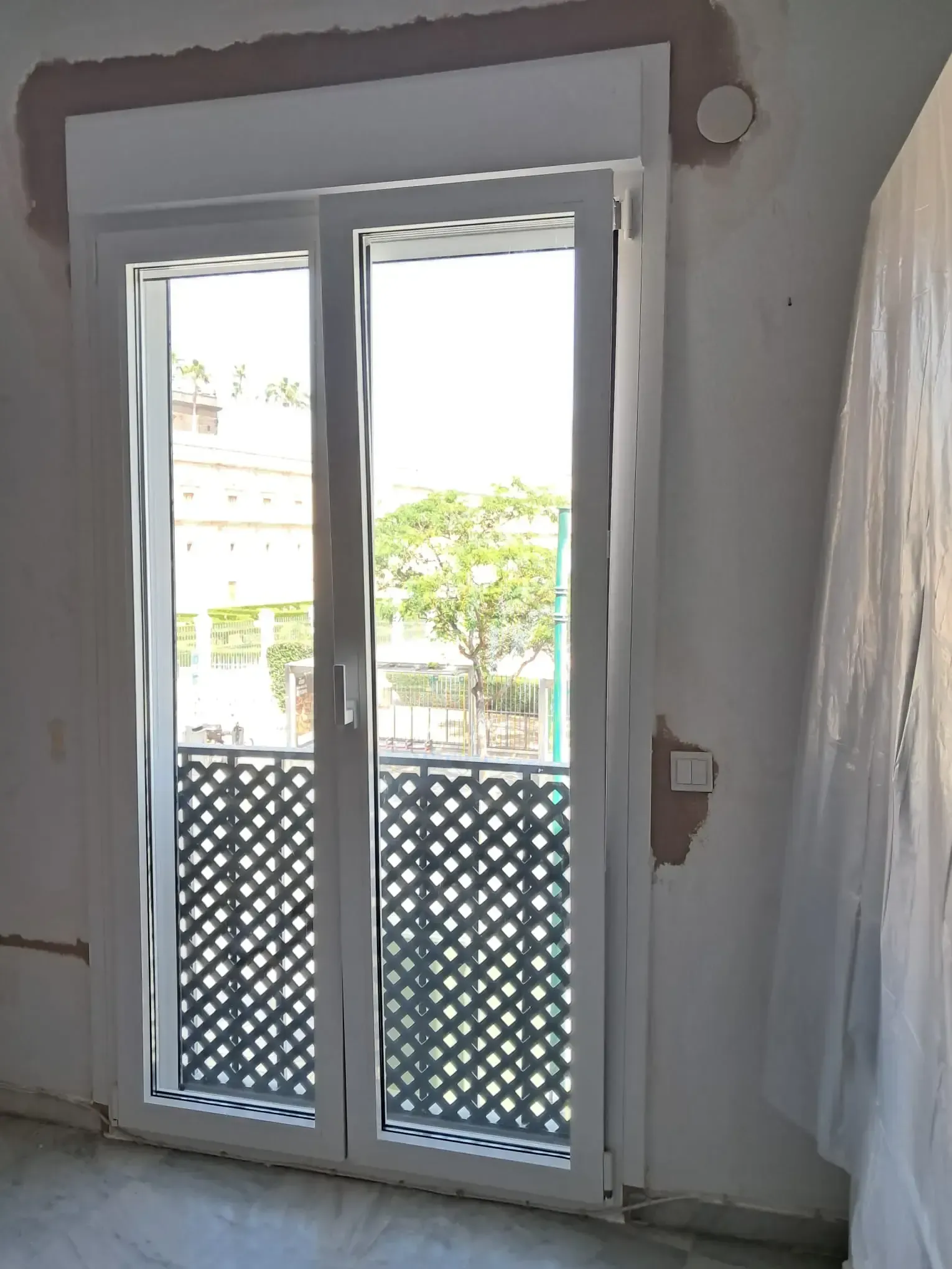 Ventana doble blanca con vista abierta, revestimiento decorativo, en una habitación con paredes sin terminar.