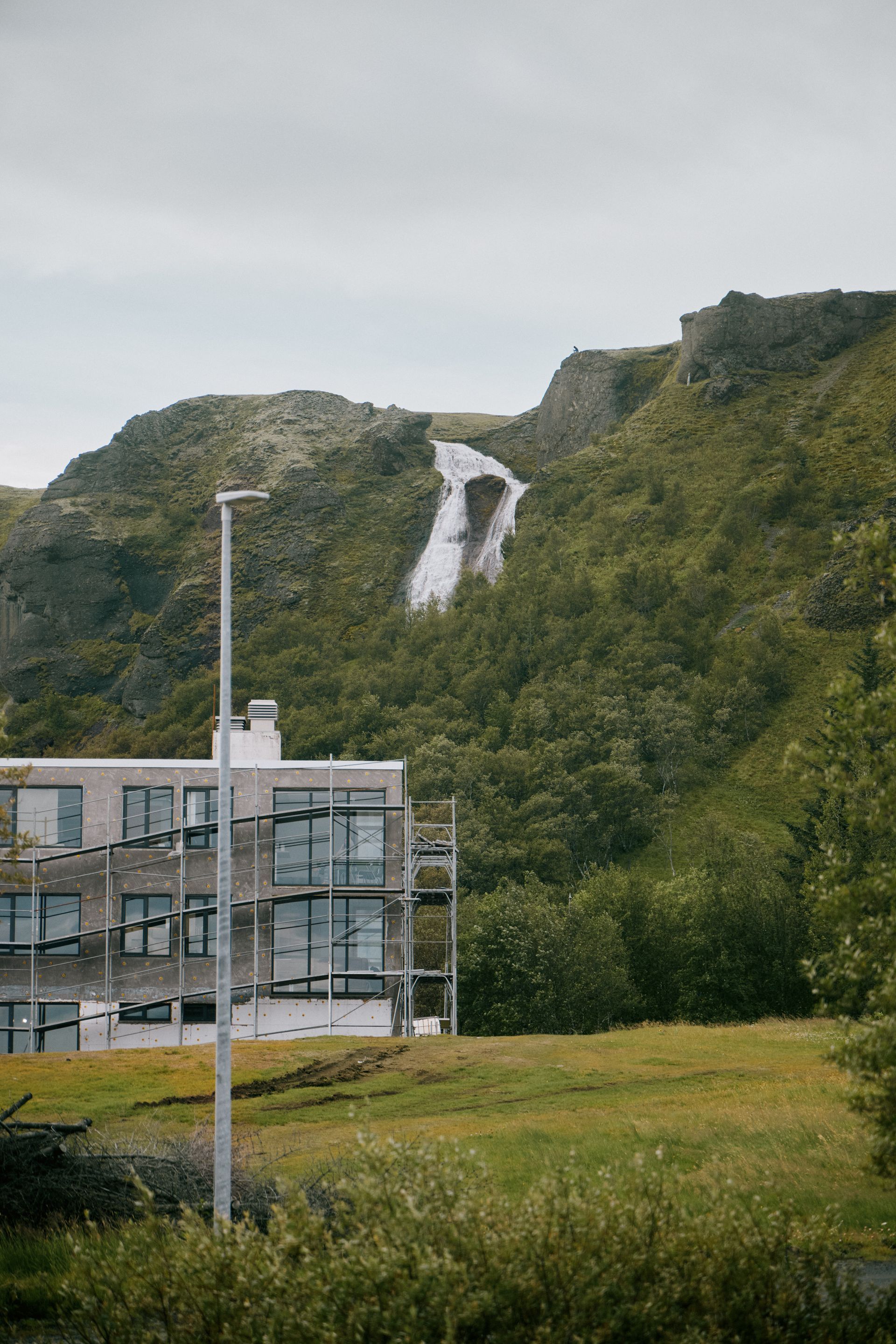 Foss er að koma niður fjallshlið við hlið byggingu.