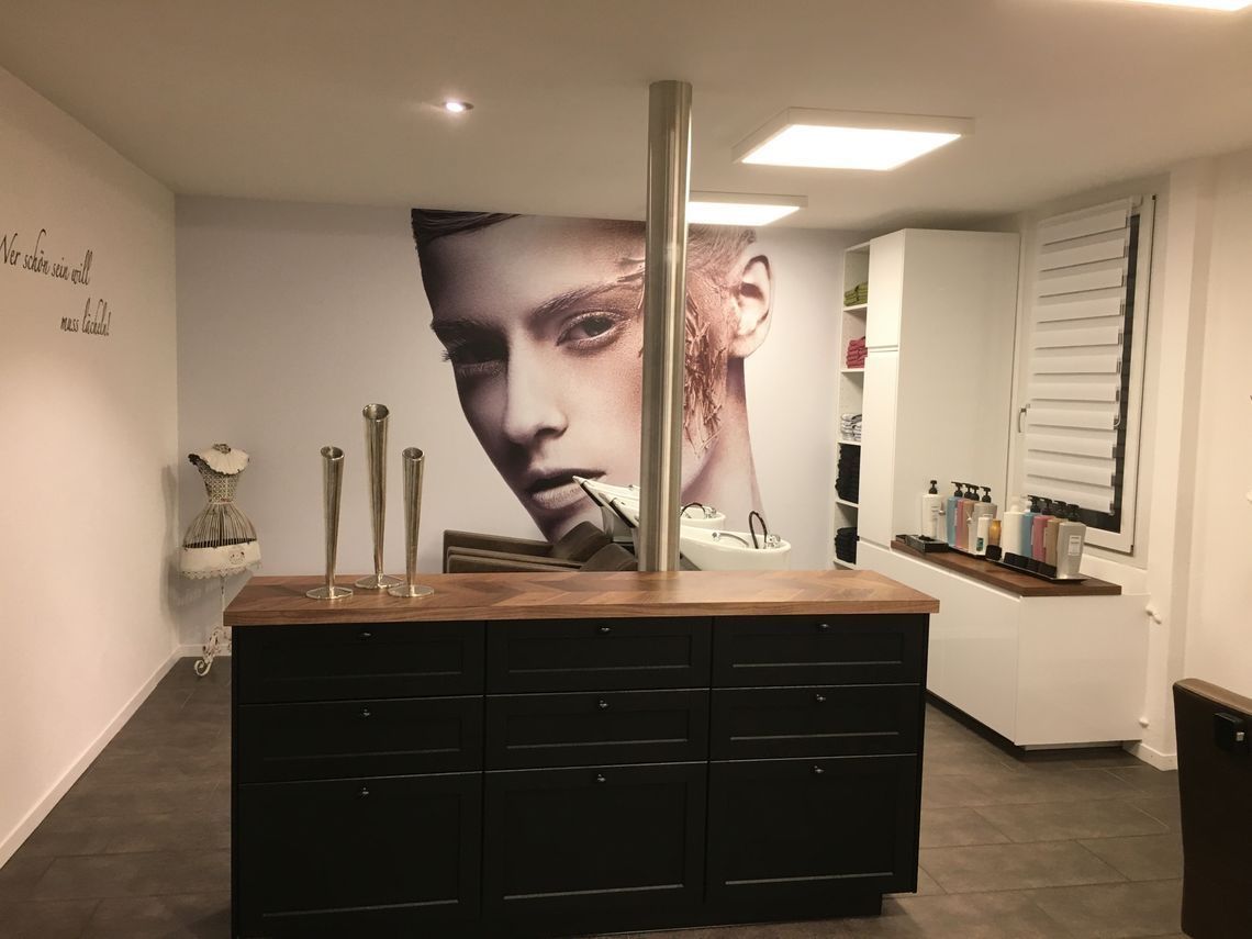 Ein Friseurraum mit einem grossen Frauenbild an der Wand. Foto vom Coiffeur Bischof