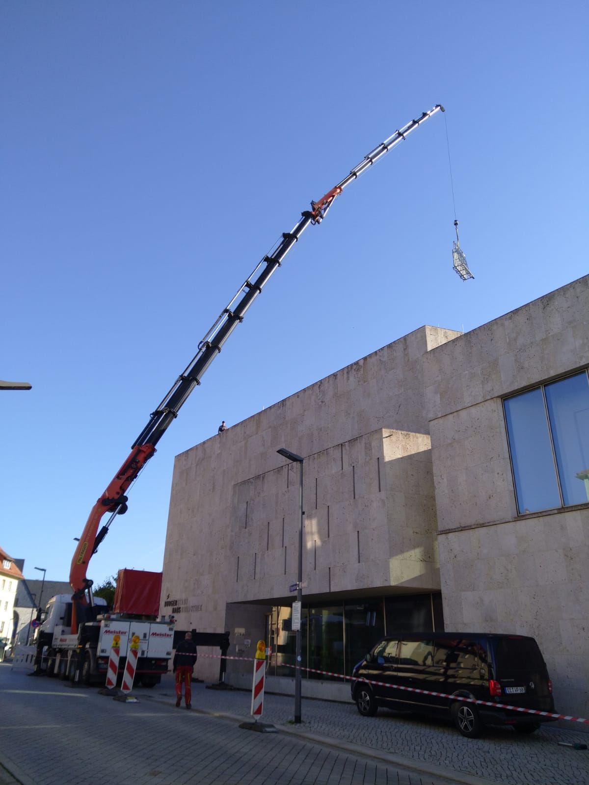 Ein LKW mit einem daran befestigten Kran steht vor einem Gebäude