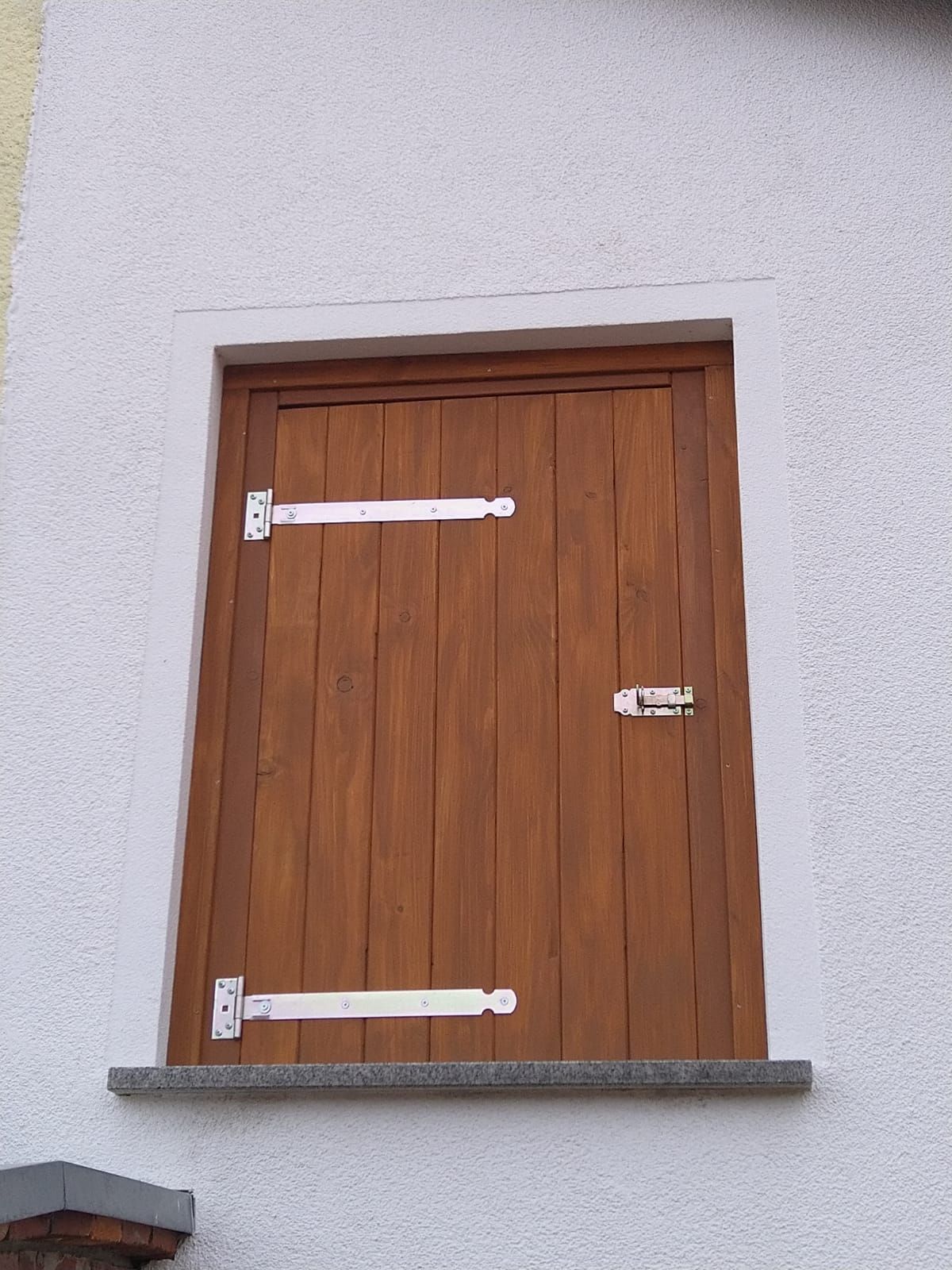 Eine Holztür an einer weißen Wand mit weißen Scharnieren