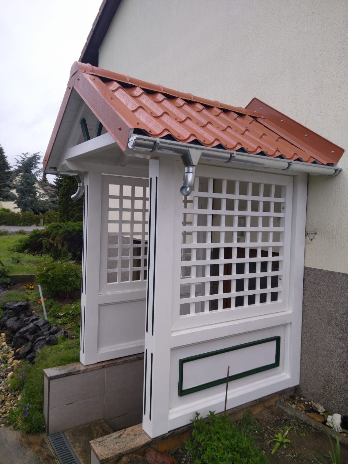 Eine weiße Veranda mit einem roten Ziegeldach an der Seite eines Hauses