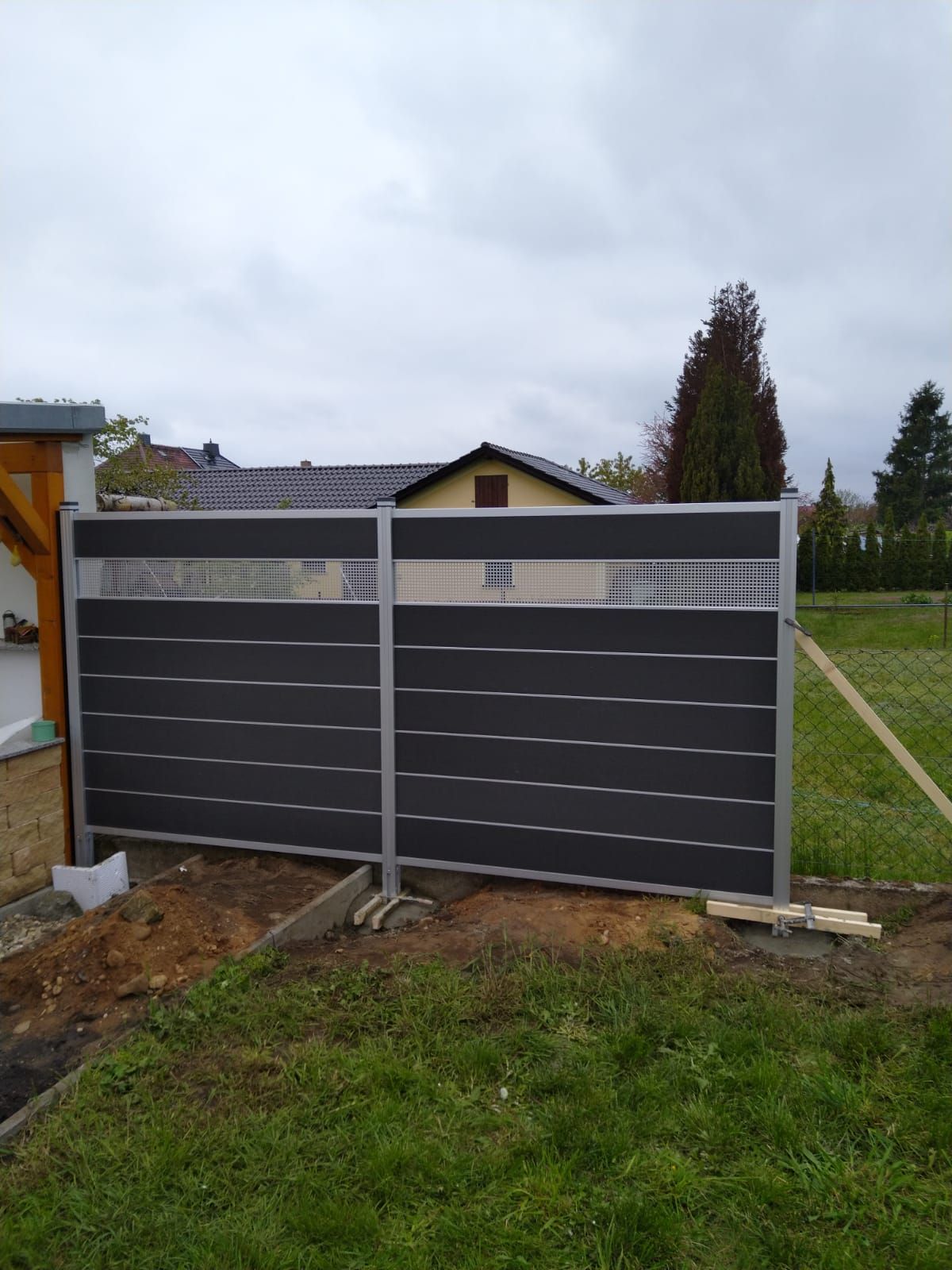 Inmitten eines üppigen grünen Feldes steht ein schwarzer Zaun.