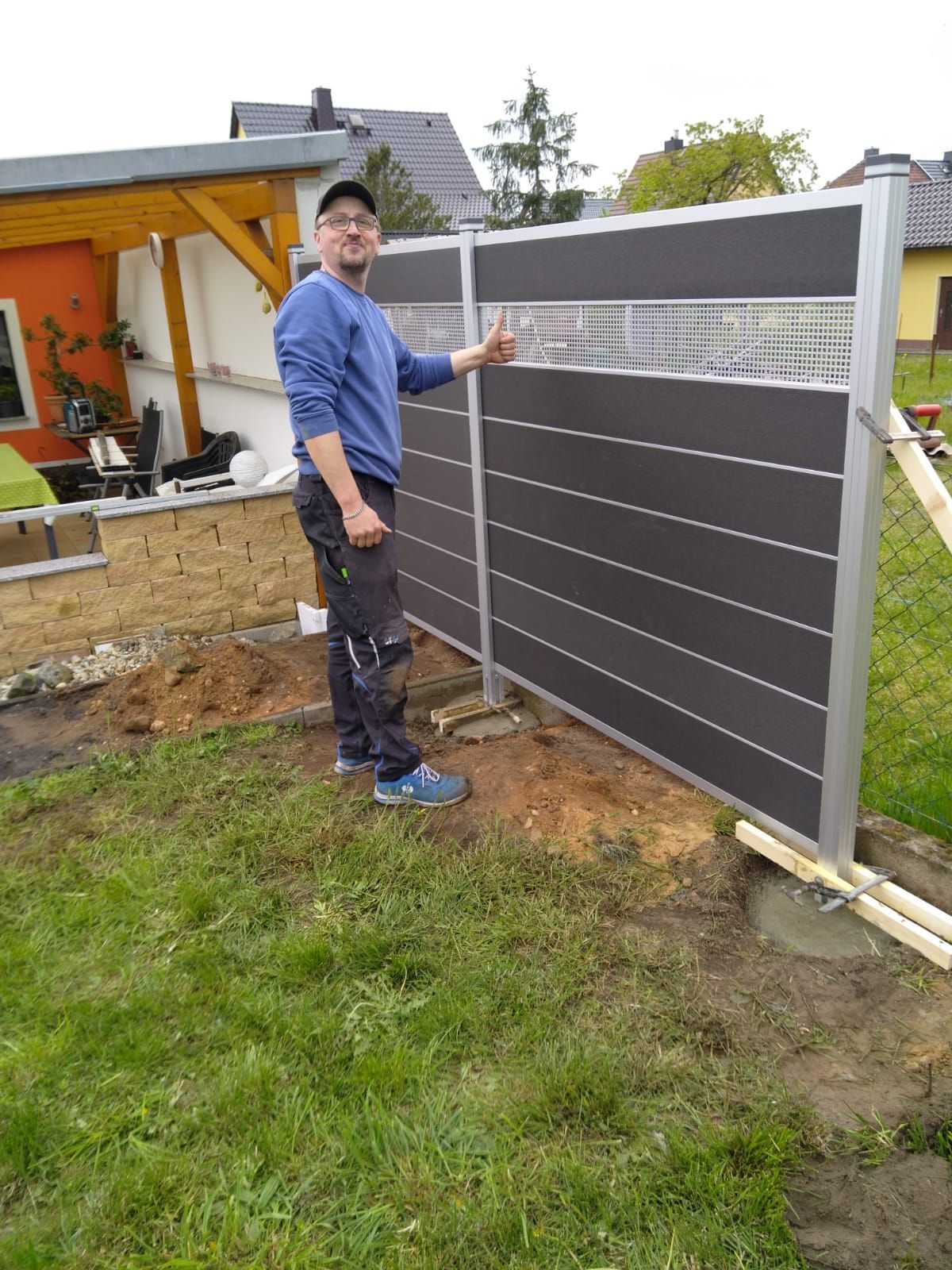 Ein Mann steht neben einem Zaun in einem Hof.