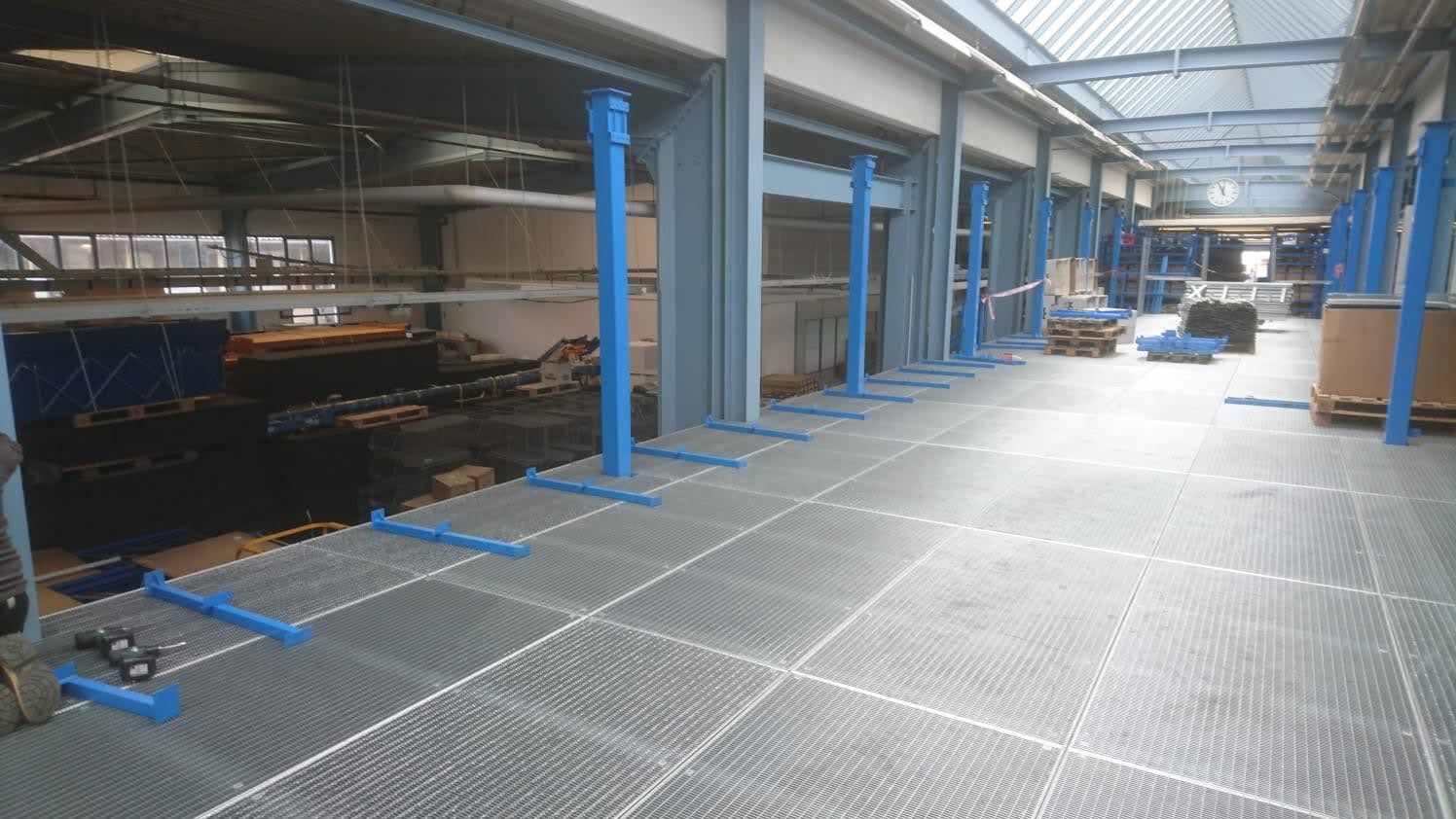 Eine große Lagerhalle mit Metallboden und blauen Stangen.