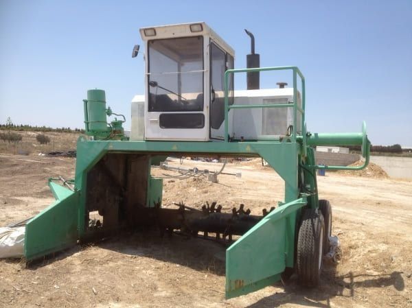 Un tractor verde y blanco está estacionado en un campo de tierra.