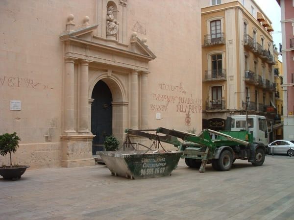 Un contenedor de basura está estacionado frente a un edificio que dice visión