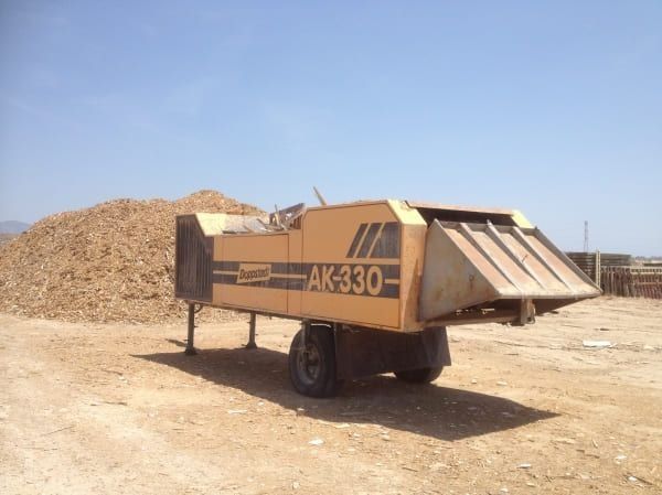 Un camión amarillo con una AK-330 al costado está estacionado en un campo de tierra.