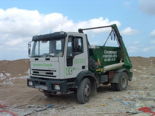 Un camión de basura está estacionado en un campo de tierra