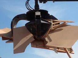 Una grúa está levantando un trozo de madera en el aire.