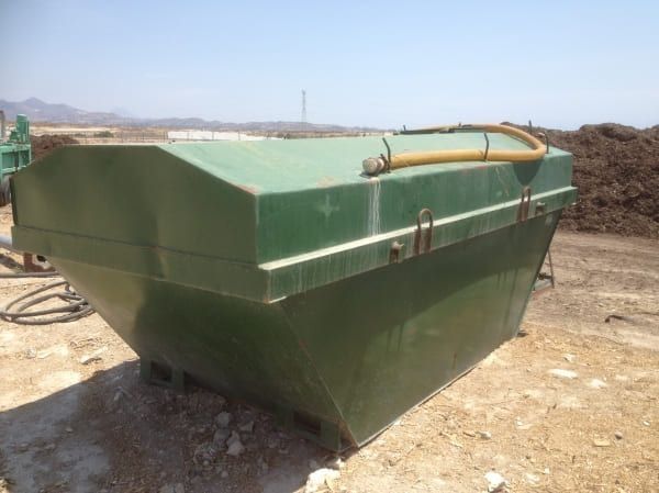 Un contenedor de basura verde con una manguera conectada a él