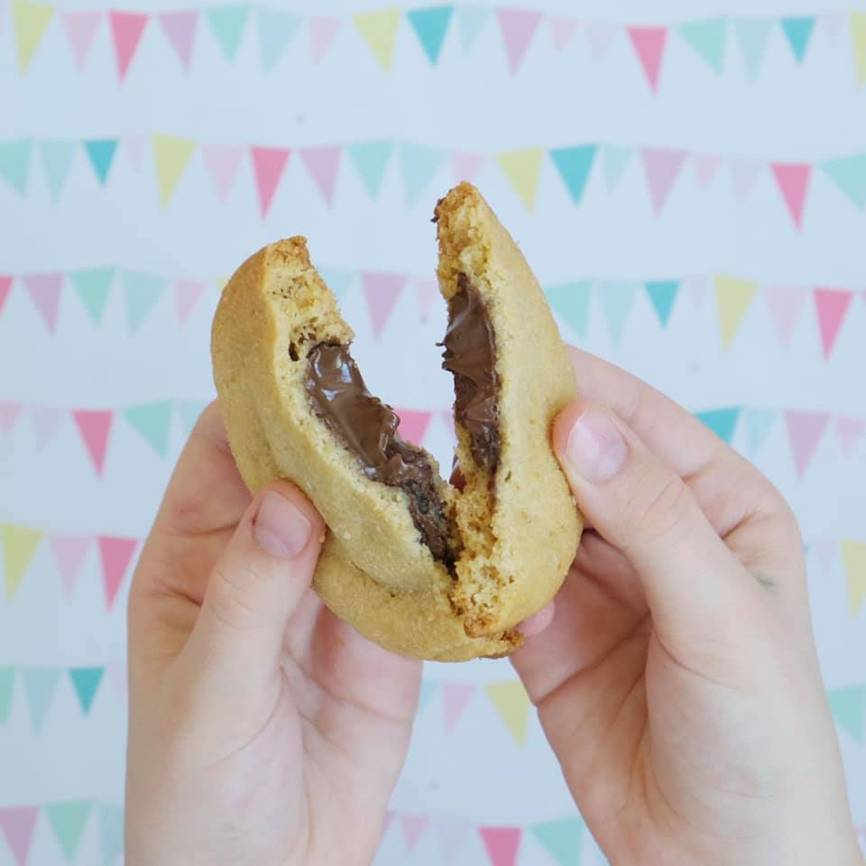 Una persona sostiene una galleta con un mordisco.