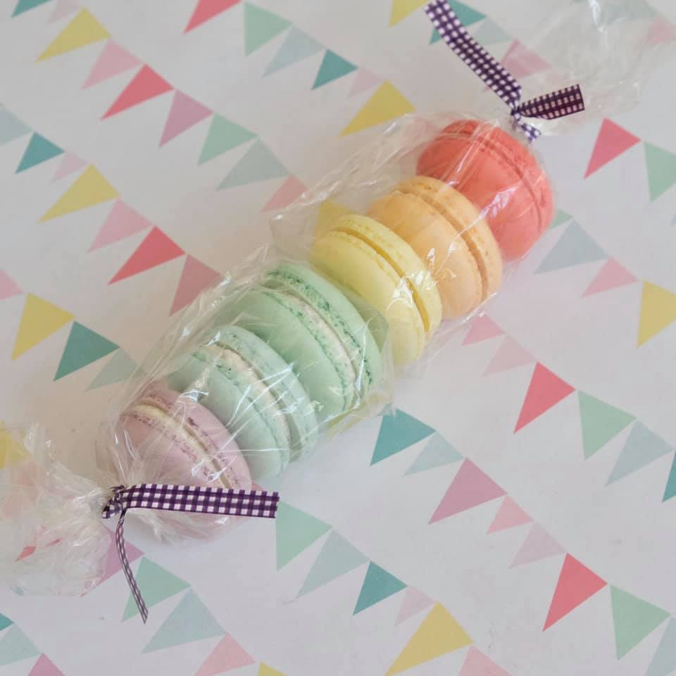 Una pila de macarons de colores del arco iris envueltos en plástico.