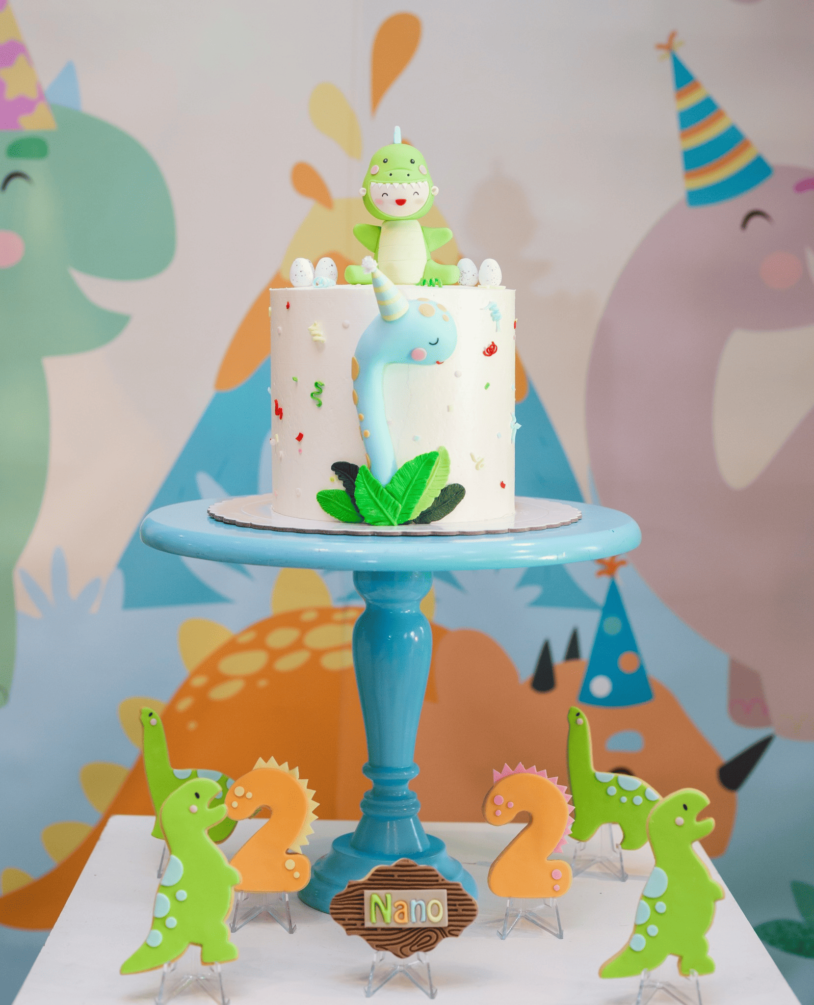 Un pastel en bandeja azul con dinosaurios verdes 