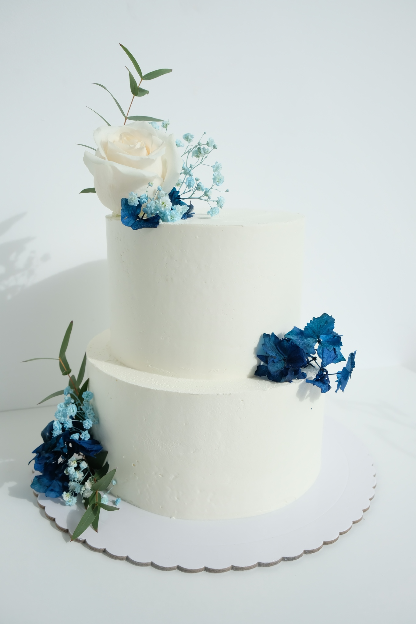 Un pastel blanco con flores azules encima.