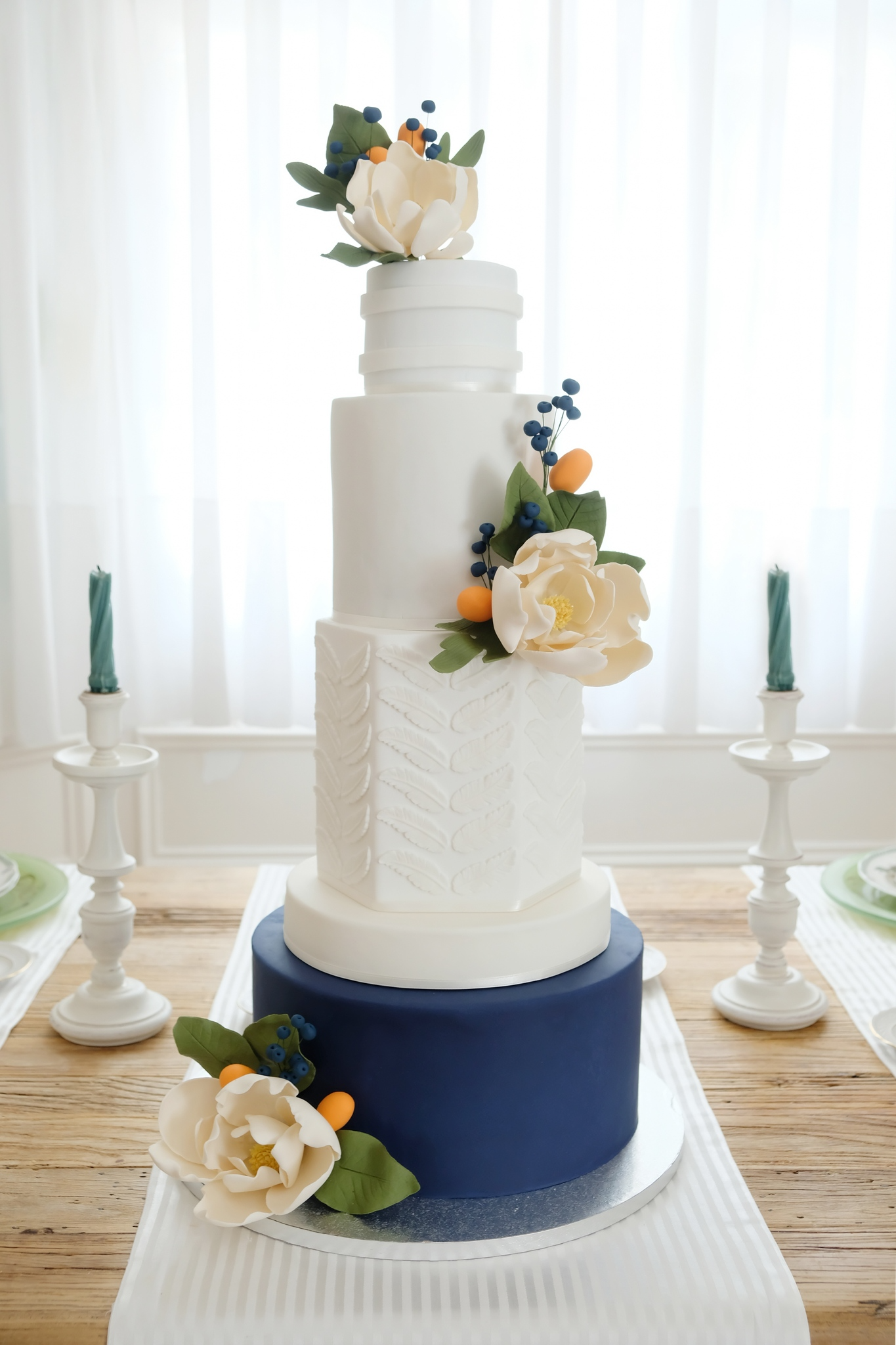 Un pastel de bodas blanco y azul está sobre una mesa de madera.