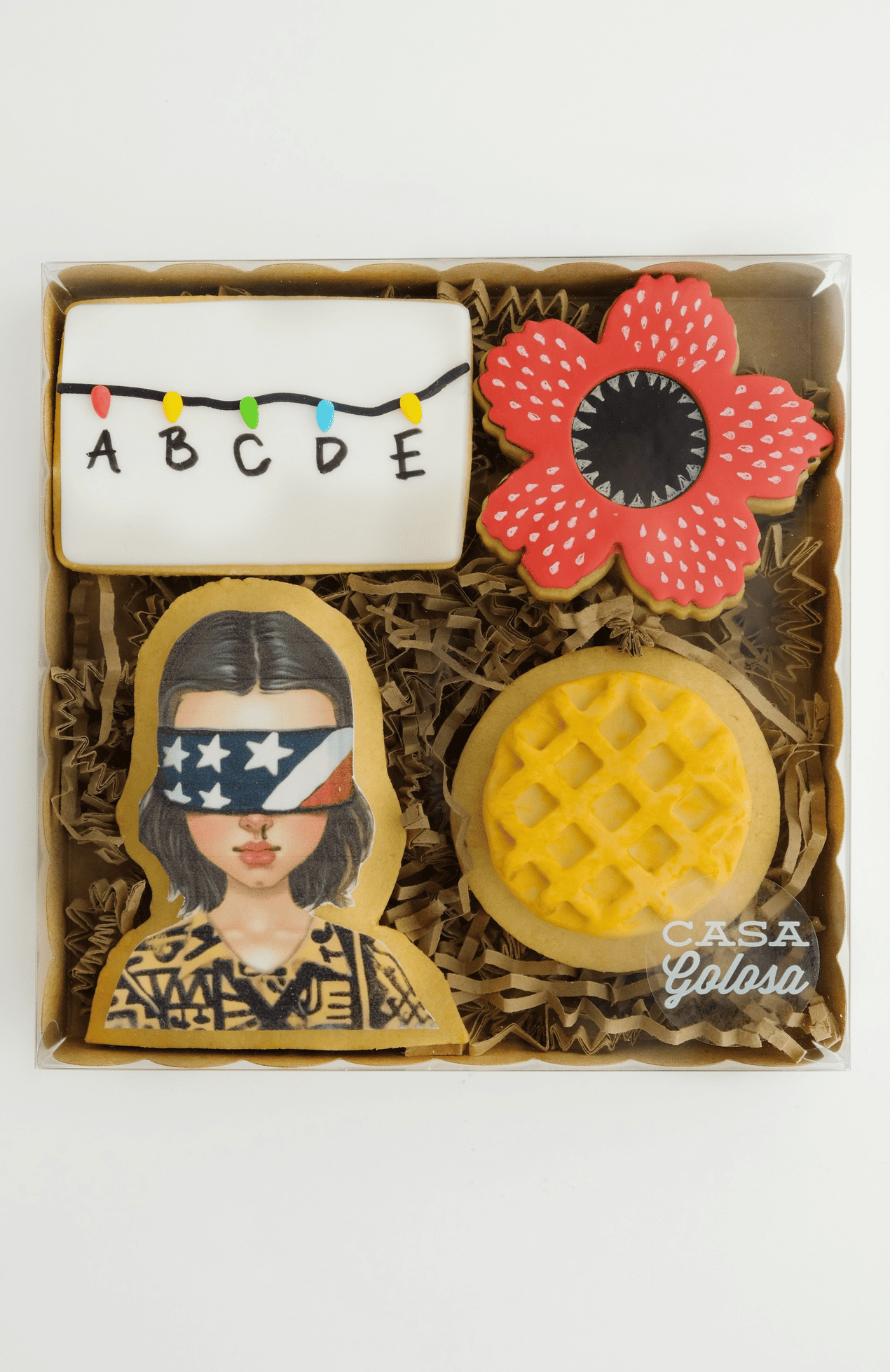Una caja llena de galletas de Stranger Things y una galleta tipo waffle.
