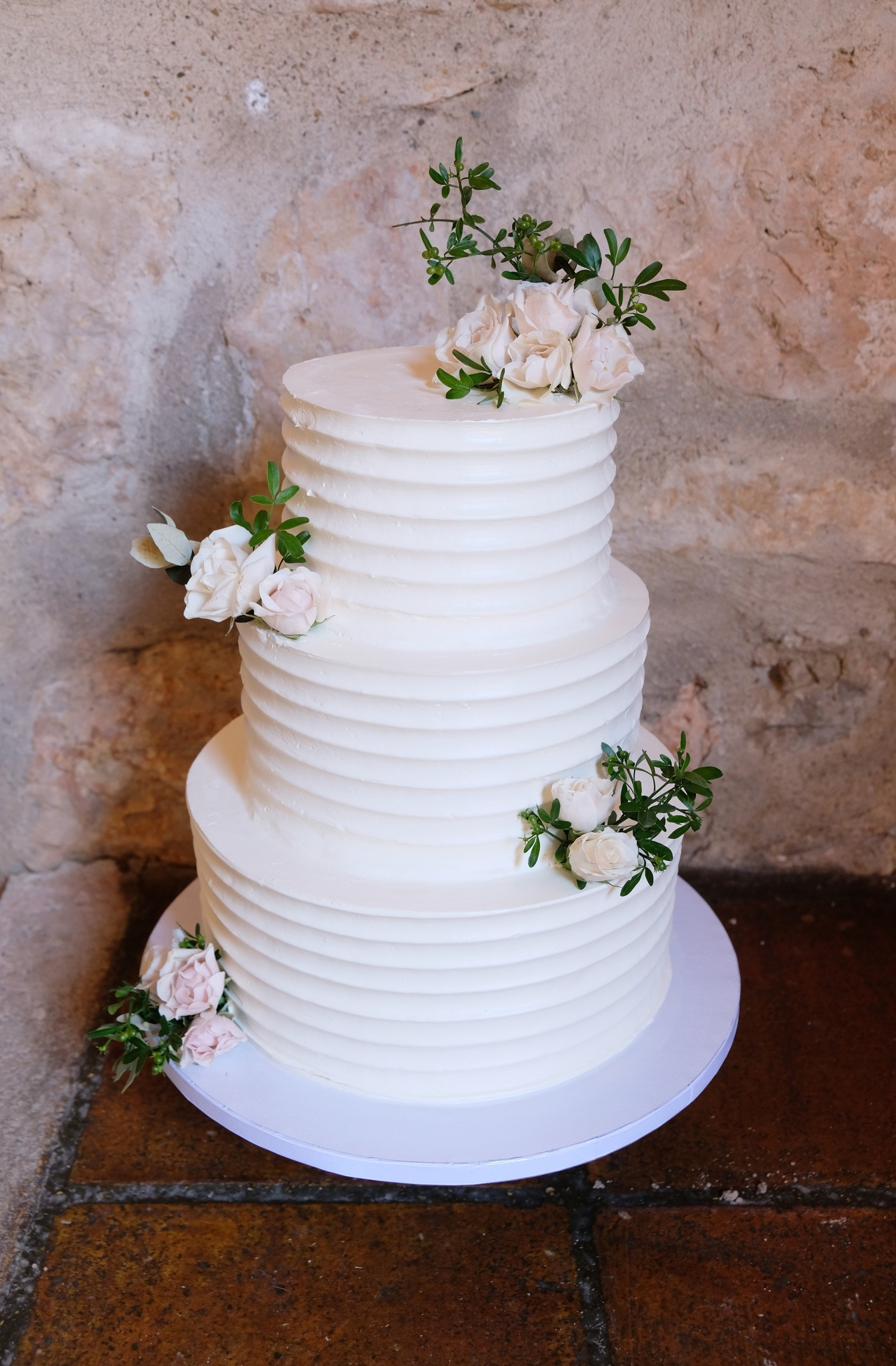 Un pastel de bodas blanco con flores encima está sobre una mesa.