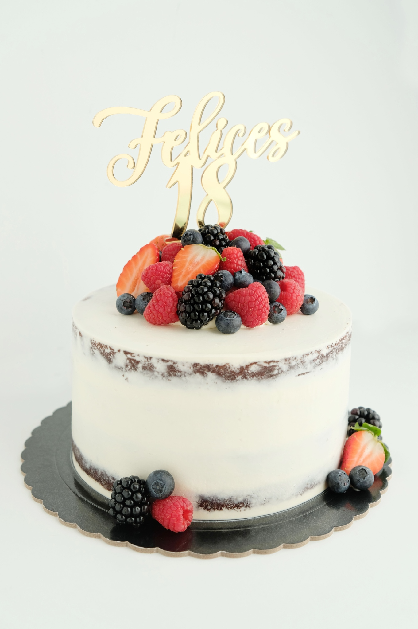 Un pastel con bayas encima y un adorno para pastel.