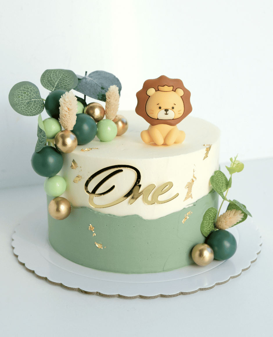 Un pastel verde y blanco con un león encima. y nombre one