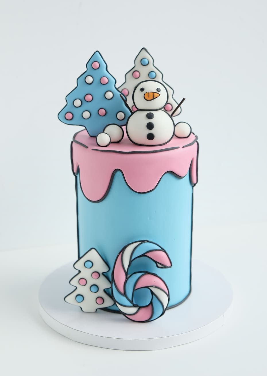 Un pastel rosa y azul con un muñeco de nieve encima.