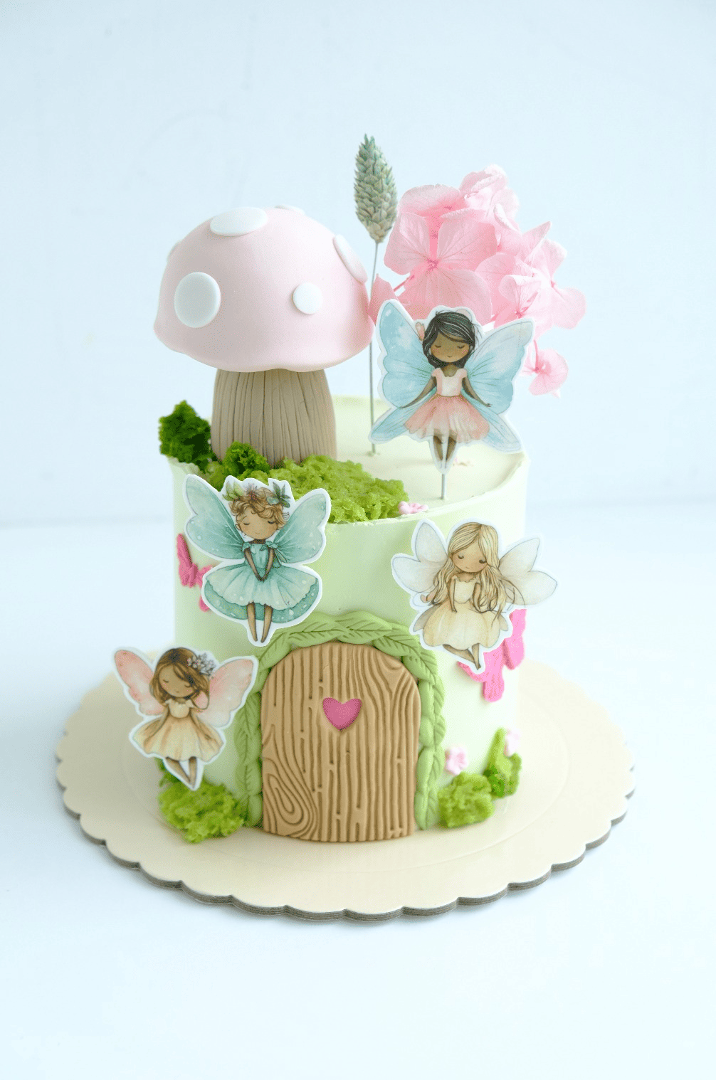 Un pastel decorado con casas de hadas, hongos y flores.