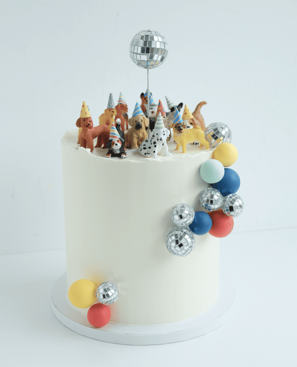 Un pastel blanco con una bola de discoteca y perros encima.